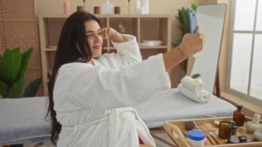Kıvrımlı bir kadın, sağlık merkezinde, güzellik ürünlerini ahşap tepside sunarken selfie çekiyor.