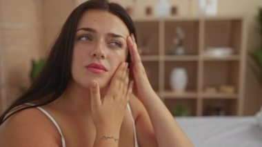 Cilt bakımını yapan kadın, arka planda sağlıkla ilgili şeylerle dolu raflarla dolu rahatlatıcı bir spa odasında kendini tedavi ve rahatlatmayı teşvik ediyor..