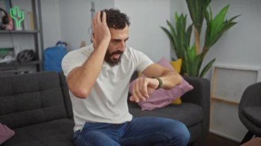 Yakışıklı, orta yaşlı bir adam. Kol saatine bakıyor, geç kalmaktan korkuyor. Beyaz tişörtlü olgun bir erkeğin kapalı çekim zamanı, toplantı için acele.