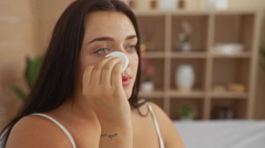 Sağlık spa merkezinde yüzüne pamuk pedi süren bir kadın. Kapalı bir güzellik salonunda, rahat bir geçmişi olan genç ve iri yarı bir kadının cilt bakımını sergiliyor.