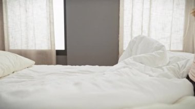 Bir kadın ve bir erkek, yumuşak ışıklı bir yatak odasında, birbirlerine sevgiyi ve birlikteliği anlatan bir yatakta samimi bir şekilde kucaklaşıyorlar..