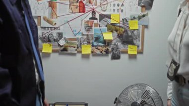 Dedektif kadın ve erkek el sıkışması arka planda kanıt panosuyla polis departmanında.