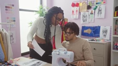 Bir kadın tasarımcı ve erkek terzi renkli bir atölyede kumaşları tartışıyor..