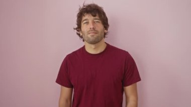 Tişörtlü neşeli, genç, İspanyol bir adam, kendine güvenen, dişlek bir gülümseme, pembe, izole bir arka plan üzerinde duran