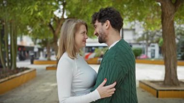 Şehir parkında ağaçlar ve banklarla kucaklaşan bir kadın ve erkek arasındaki özel an aşkı ve ilişkiyi simgeliyor..