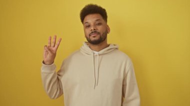Kapüşonlu neşeli Afro-Amerikalı adam kendinden emin bir şekilde işaret ediyor, 