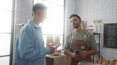 Erkek müşteri fırından hamur işi satın alıyor. İyi aydınlatılmış modern bir iç mekanda bir kart ödeme terminali kullanarak.