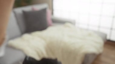 Bir labrador köpeği, bir kadının eli emir verirken ahşap bir zeminde, yumuşak bir battaniyeyle, bir kanepenin yanında oturur..