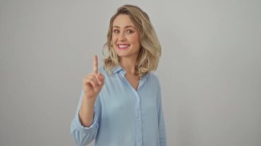 Kendine güvenen genç sarışın bir kadın, neşeli bir gülümseme, bir gömlek içinde dikiliyor, hevesle yukarı bakıyor, bir numaralı işareti parmağıyla izole edilmiş beyaz arka planda gösteriyor.