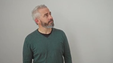 Süveter giyen genç adam gülümseyip yan tarafa bakıyor ve düşünüyor. izole edilmiş beyaz arkaplan