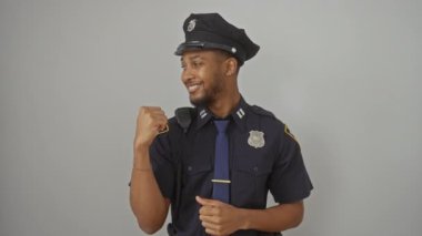 Polis üniformalı neşeli Afro-Amerikan adam, başparmak kaldırıyor, tüm gülüşleri güvenilir bir görünüm ile, beyaz izole bir arka planı işaret ediyor