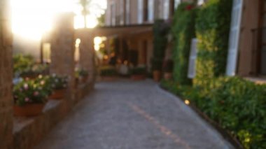 Çiçeklerle ve yeşilliklerle kaplı bulanık bir yol Mallorca 'da taş bir binaya çıkıyor, günbatımında İspanya, odaktan uzak, canlı renklerle ve doğal güzellikle dolu bir manzara sergiliyor..