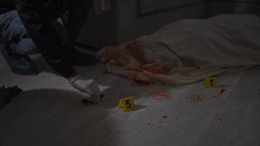 Adam olay yeri kanıtlarını kapalı bir alanda inceliyor. Detaylara odaklanıp dikkatle inceliyor..