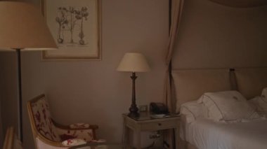 Lüks beyaz yatak odası, klasik koltuk, ahşap komodin ve sanat eserleri..