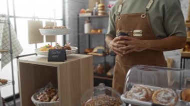 Adam, glütensiz hamur işleri ve çeşitli ekmek seçenekleriyle dolu bir fırında müşteriye kahve veriyor.