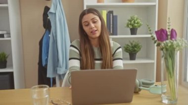 Genç İspanyol kadın, ofis ortamında bir mola sırasında geriniyor, rahatlık ifade ediyor..
