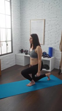 Hamile İspanyol kadın, spor salonunda dambıllarıyla egzersiz yapıyor. Spor ve iyi donanımlı bir spor merkezinde annelik egzersizlerini sergiliyor..