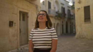 Çizgili gömlekli genç bir İspanyol kadın büyüleyici bir caddede duruyor. Lecce, puglia, italyan, coşkulu mutluluk ve rahatlama..