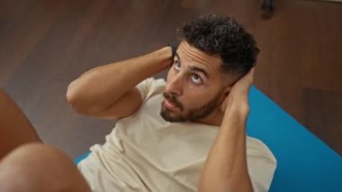 Çekici genç İspanyol bir adam, kapalı bir spor salonundaki yoga minderinde mekik çekiyor..