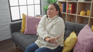 Rahat, orta yaşlı bir İspanyol kadın renkli yastıklarla rahat bir oturma odasında dinleniyor.