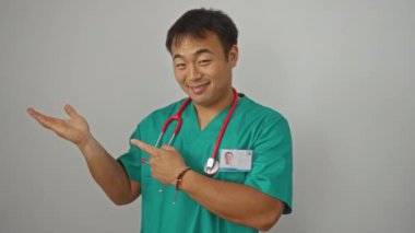 Üniformalı doktor, Çinli genç bir adam gülümseyip şaşkınlıkla işaret ederken izole edilmiş beyaz bir arka plan sunuyor.
