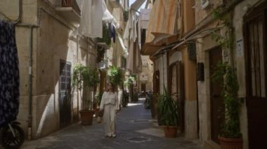 Genç İspanyol kadın, Avrupa 'nın atmosferini yükselten kirli çamaşırları ve saksı bitkileriyle İtalya' nın Bari şehrinin büyüleyici eski sokaklarında geziniyor..