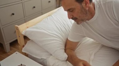 Yaşlı adam rahat bir yatak odasında beyaz yatak ve ahşap mobilyalarla huzur içinde uyuyor.