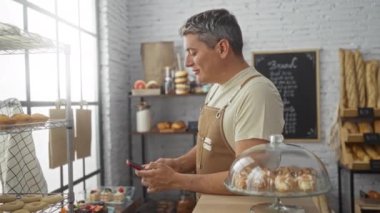 Fırında çalışan genç bir adam gün boyunca etrafını lezzetli pastalarla çevirmiş telefonunu kontrol ediyor.