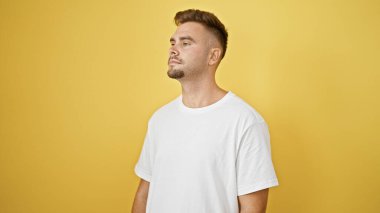 Sakallı, beyaz tişörtlü, sarı arka planda izole edilmiş yakışıklı İspanyol bir adam..