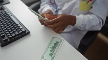 Klinikteki Afrikalı Amerikalı bir kadın elinde bilgisayar klavyesi olan bir masada bize dolar sayıyor..