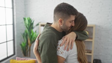 Sevgi dolu bir çift sıcak bir evde kucaklaşır, şefkat ve beraberliği ifade eder..