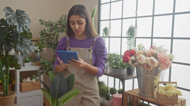 Çiçek ve buketlerle çevrili bir çiçekçide tablet kullanan İspanyol kadın modern bir çiçekçi havası veriyor..