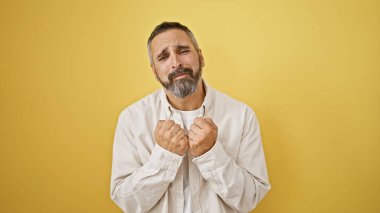 Sakallı, gri saçlı, sarı izole edilmiş arka planda sıkıntılı, yaşlı bir İspanyol.