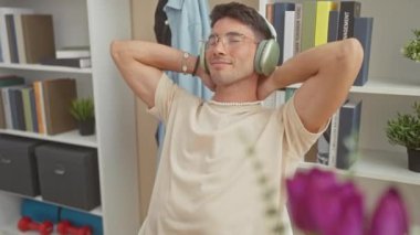 Dinlenmiş İspanyol adam modern bir oturma odasında kulaklıkla müzik dinliyor..