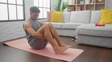 Yoga yapan bir adam evde pilates yapıyor. Oturma odasında spor yapıyor.