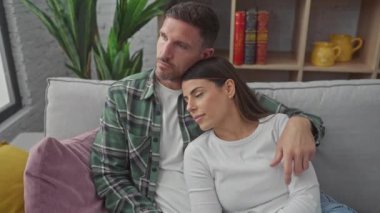 Sevgi dolu bir çift, sıcak bir oturma odasındaki kanepede sarılır, samimiyet ve rahatlık hissini canlandırır..