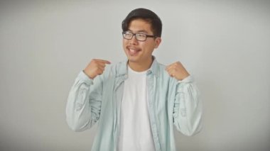 Gözlüklü neşeli genç Çinli adam gururla kendini işaret ediyor, beyaz soyutlanmış arka plana karşı güven saçıyor.