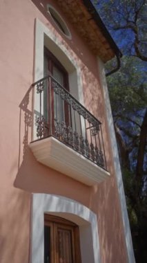 Pembe Akdeniz ev cephesi dekoratif balkon, pencere, kapı ve güneşli ortamda gölgeler.