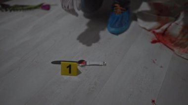 Kel dedektif olay yerindeki adli kanıtları inceliyor.