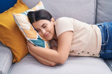 Young beautiful hispanic woman lying on sofa sleeping at home