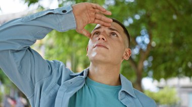 Yakışıklı, İspanyol asıllı bir adam şehir parkında yukarı bakıyor, rahat ve çekici..