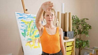 Genç bir kadın sanatçı, renkli tablosunu parlak bir stüdyo ortamında değerlendirerek yaratıcılık ve odaklanma sergiliyor..