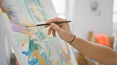 Parlak bir sanat stüdyosunda genç bir adamın tuvale yaptığı resim.