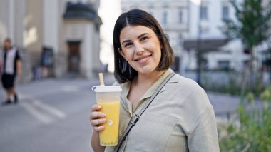 Genç ve güzel İspanyol kadın Viyana sokaklarında köpüklü çay içiyor.