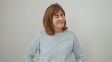 Neşeli orta yaşlı bir kadın kameraya seksi bir ifadeyle göz kırpıyor, izole beyaz arka planda duran bir kazak giyiyor. Mutlu yüz neşe ve eğlence dolu!