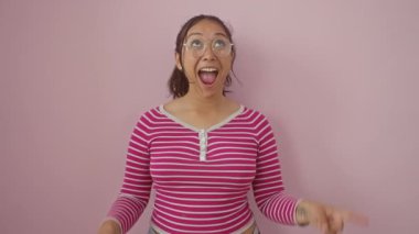 Sürpriz, çizgili tişörtlü İspanyol bir kadının yüzündeki neşe. Yukarı bakıyor, şaşkın şaşkın bakıyor. Pembe ve izole bir arkaplanda..