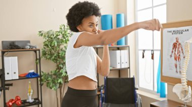 Arka planda spor salonunda spor yapan Afrikalı Amerikalı kadın.