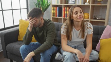 Üzgün adam ve destekleyici kadın rahat bir oturma odasında kanepede oturup ilişki dinamiklerini canlandırıyorlar..