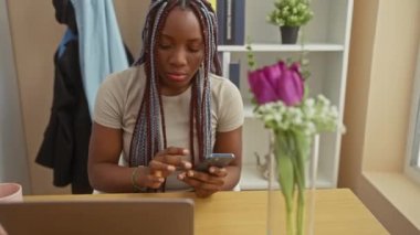 Kurulumda akıllı telefon ve laptop kullanan odaklanmış Afrikalı bir kadın.