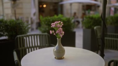 Lecce, İtalya 'da beyaz bir masadaki vazoda canlı çiçekler sergilenen büyüleyici bir açık hava kahvesi. 